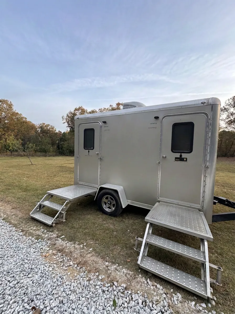 Augusta VIPee restroom trailer set up on a grass field with fold-down steps at each door